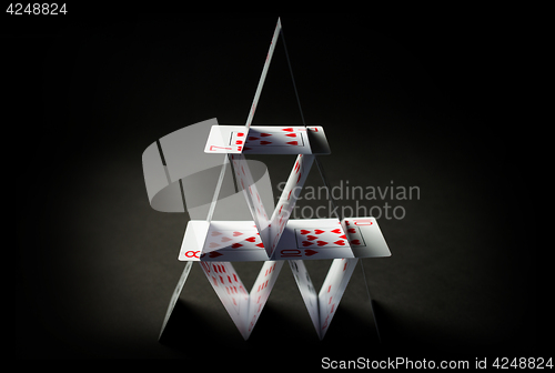 Image of house of playing cards over black background
