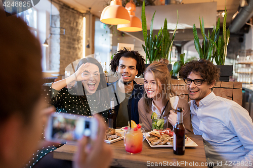 Image of friends with smartphone photographing at cafe