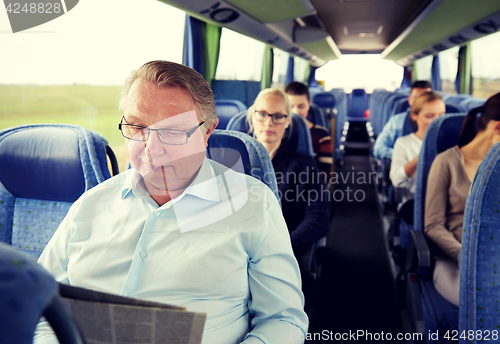 Image of happy senior man reading newspaper in travel bus