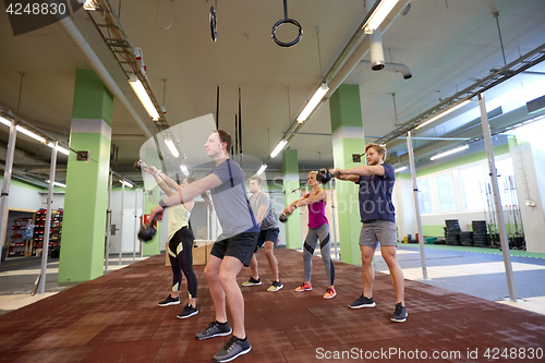 Image of group of people with kettlebells exercising in gym