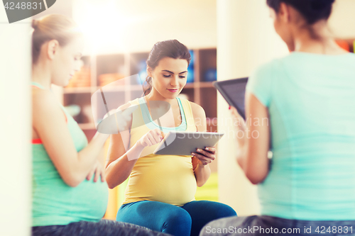 Image of happy pregnant women with gadgets in gym