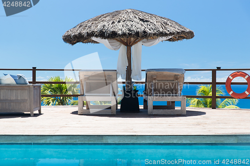 Image of palapa and sunbeds at seaside swimming pool