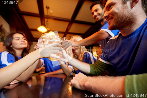 Image of football fans clinking beer glasses at sport bar