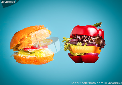 Image of The healthy sandwich with fresh pepper, onion, salad lettuce and unhealthy harmful hamburger