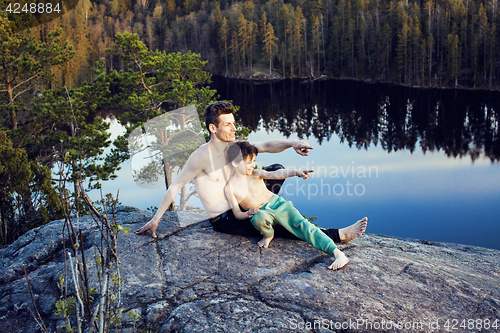 Image of middle age man with little cute son doing sport yoga on the top of the mountain together, happy family lifestyle people outdoor, summer wild nature for training