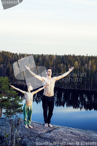 Image of middle age man with little cute son doing sport yoga on the top of the mountain together, happy family lifestyle people outdoor, summer wild nature for training