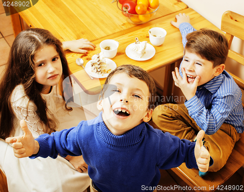 Image of little cute boys eating dessert on wooden kitchen. home interior
