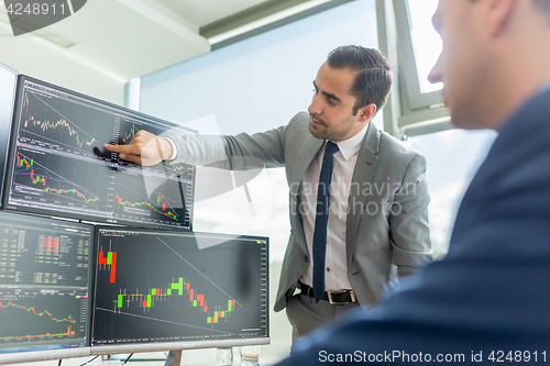 Image of Stock brokers looking at computer screens, trading online.