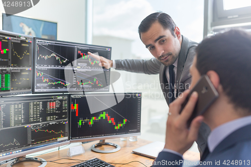 Image of Stock brokers looking at computer screens, trading online.