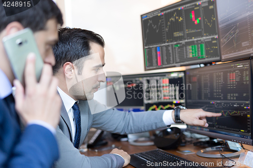 Image of Stock brokers looking at computer screens, trading online.