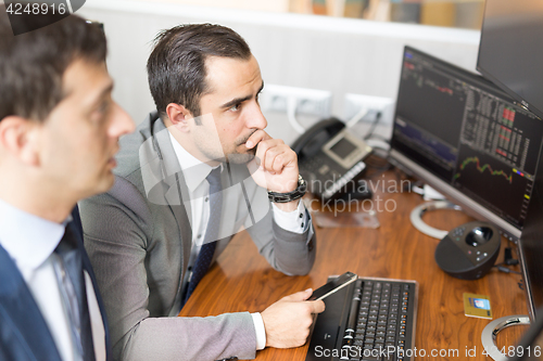 Image of Stock brokers looking at computer screens, trading online.