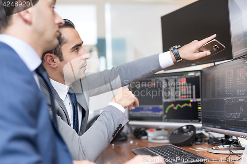 Image of Stock brokers looking at computer screens, trading online.