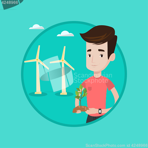 Image of Worker of wind farm holding green small plant.