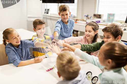 Image of happy children holding hands at robotics school