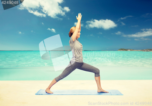 Image of woman making yoga warrior pose on mat