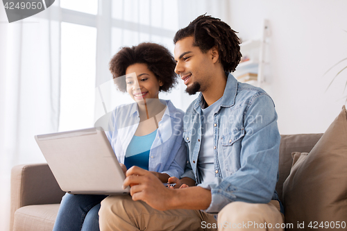 Image of smiling happy couple with laptop at home
