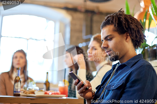 Image of man with smartphone and friends at restaurant