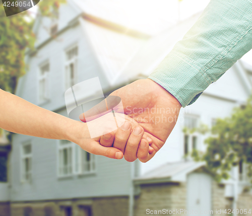 Image of father and child holding hands over house