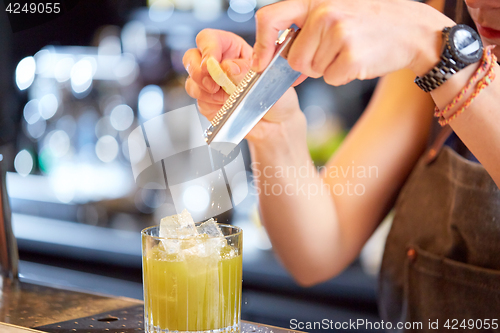 Image of bartender grates chocolate to cocktail at bar
