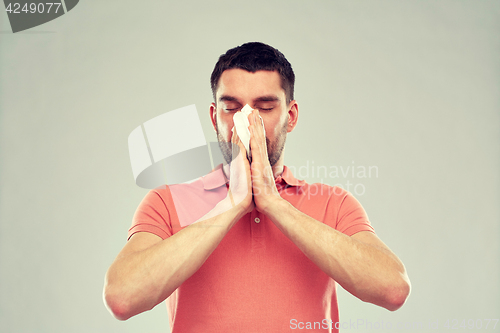 Image of sick man with paper napkin blowing nose