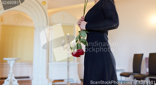 Image of sad woman with red rose at funeral in church