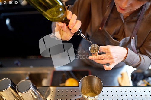Image of bartender pouring alcohol into jigger at bar