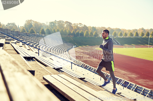 Image of happy young man running upstairs on stadium