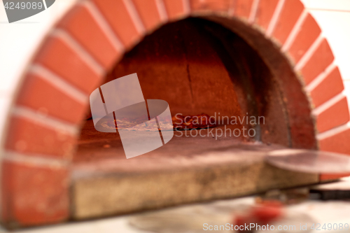 Image of pizza baking in oven at pizzeria