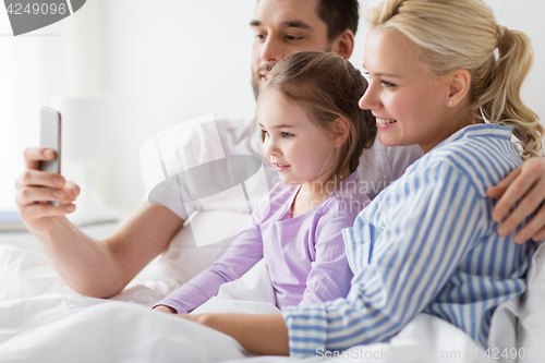 Image of happy family taking selfie by smartphone at home