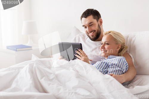 Image of smiling happy couple with tablet pc in bed at home