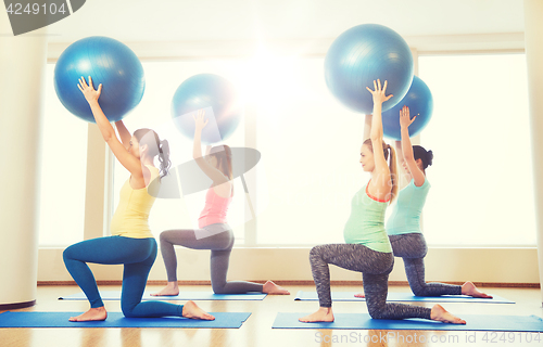 Image of happy pregnant women exercising with ball in gym