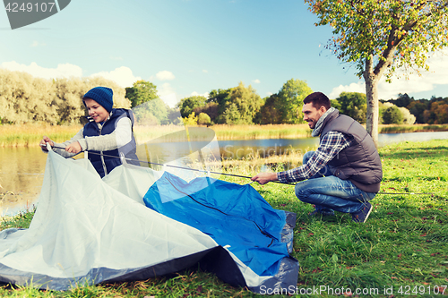 Image of happy father and son setting up tent outdoors