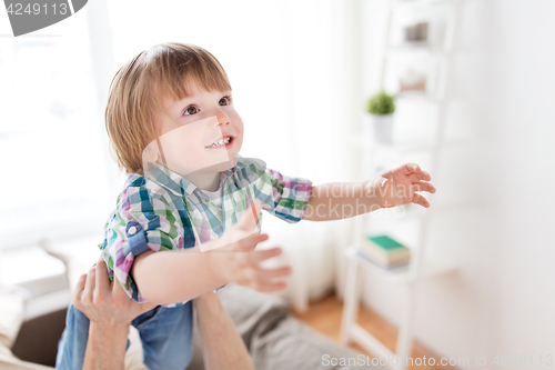 Image of father hands holding happy little boy at home