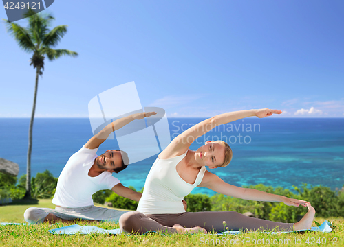 Image of happy couple making yoga exercises outdoors