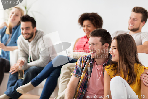 Image of happy friends watching tv at home