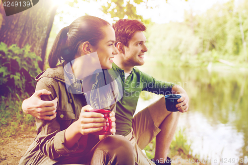 Image of happy couple with cups drinking in nature