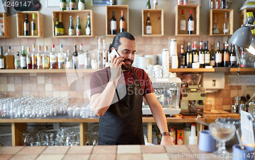 Image of happy man or waiter at bar calling on smartphone