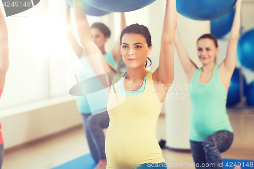 Image of happy pregnant women exercising with ball in gym
