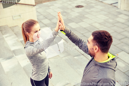 Image of smiling couple making high five on city street