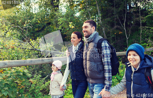 Image of happy family with backpacks hiking in woods