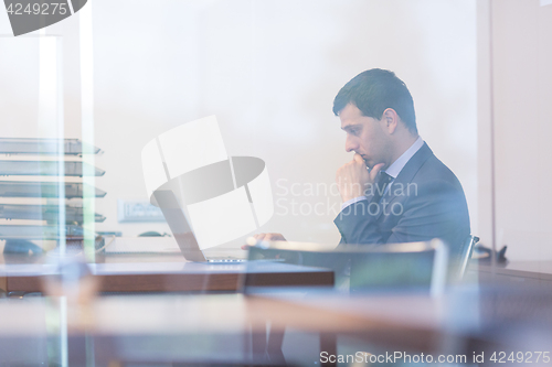 Image of Elegant businessman analyzing data in modern office.