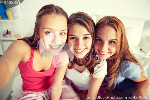 Image of happy friends or teen girls taking selfie at home