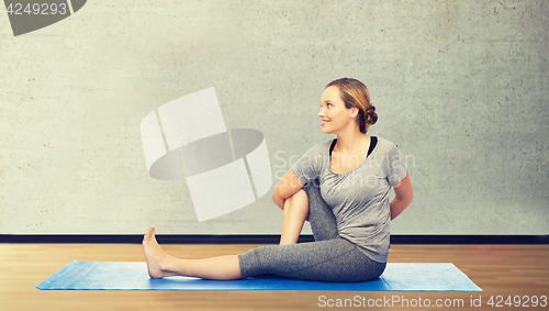 Image of woman making yoga in twist pose on mat