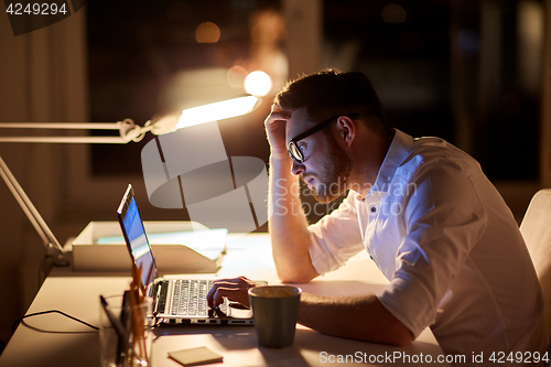 Image of businessman typing on laptop at night office