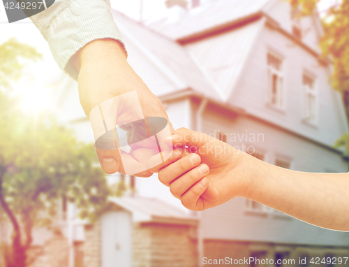 Image of father and child holding hands over house