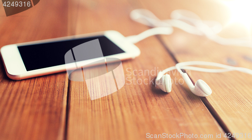 Image of close up of blank smartphone and earphones on wood