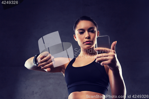 Image of woman with heart-rate watch and smartphone in gym