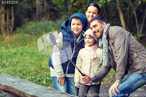 Image of happy family with smartphone selfie stick at camp