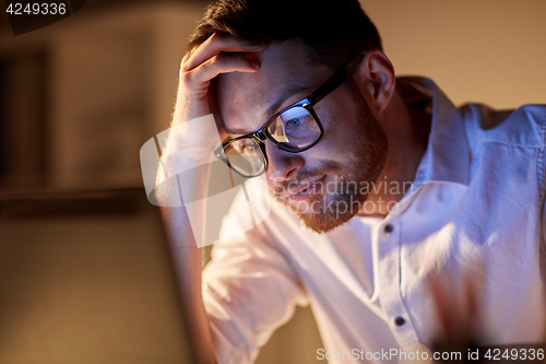Image of businessman with laptop thinking at night office