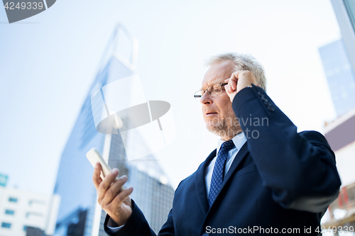 Image of senior businessman with smartphone in city
